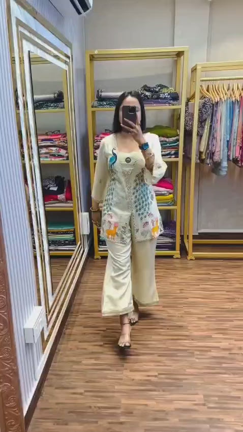 Woman wearing a cream ethnic co-ord set with heavy embroidery, peacock and deer designs, and shimmer silk fabric

